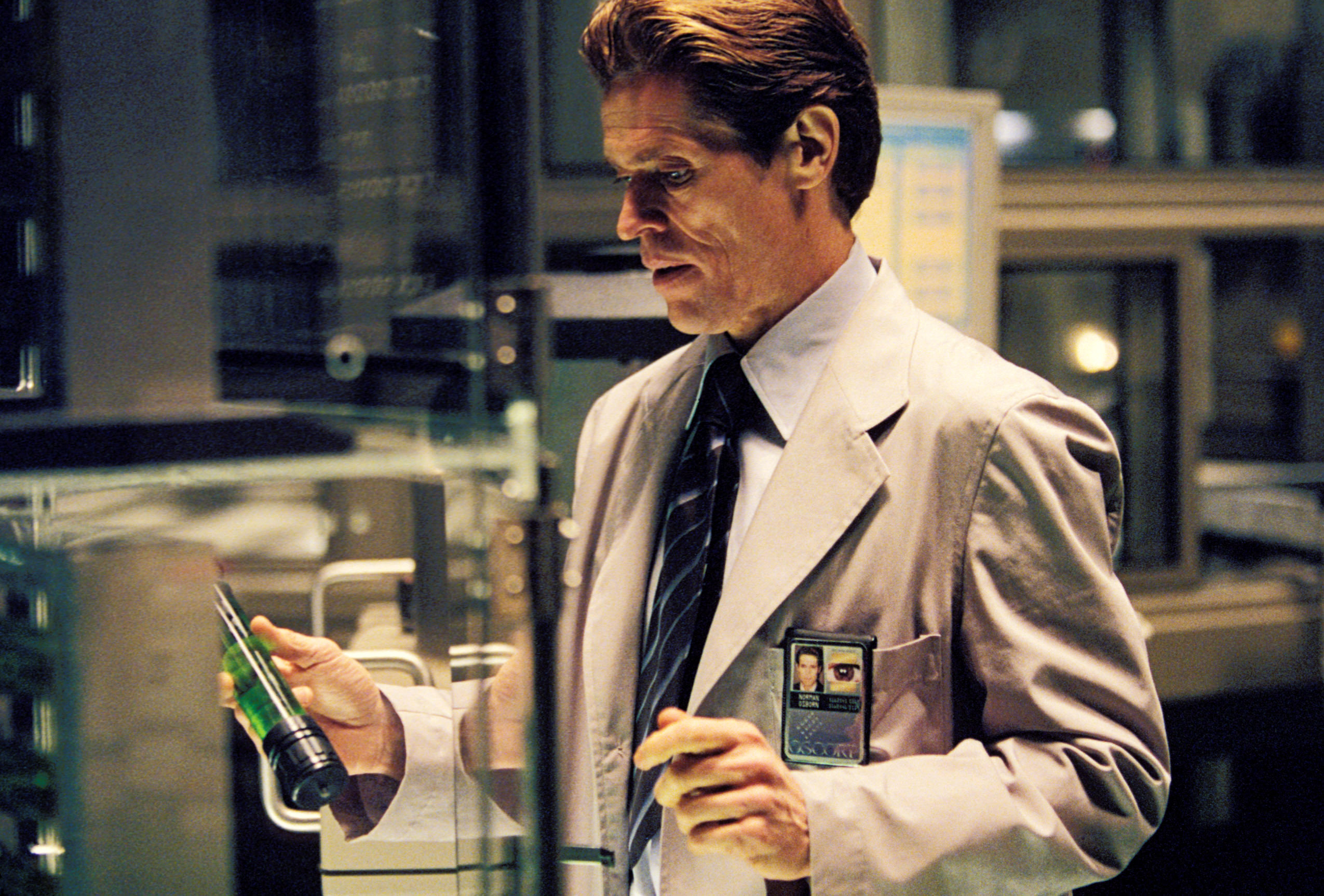 Willem Dafoe in a lab coat and lab setting, holding a test tube in "Spider-Man"