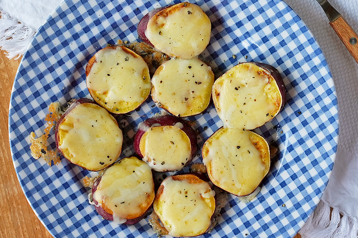 チェック柄の皿に盛り付けられた焼きチーズポテト。フォークが横に置かれている。