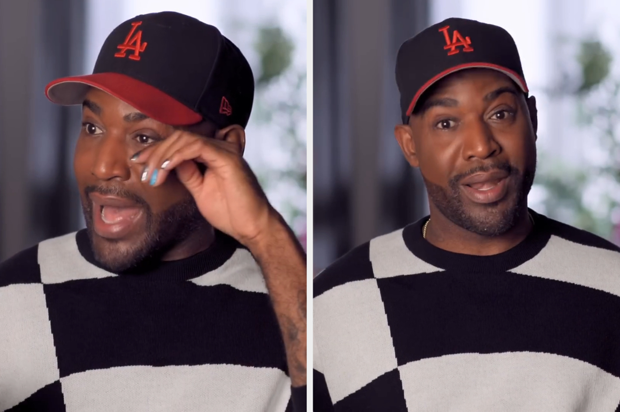 Karamo Brown in a checkered sweater and LA baseball cap, wiping a tear and then speaking expressively