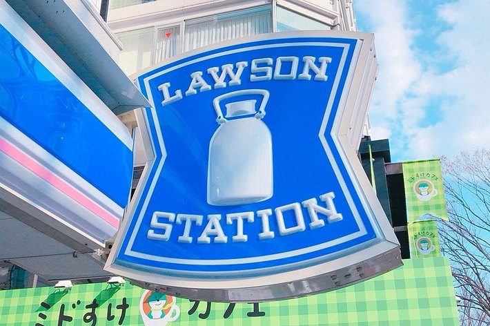 ローソンの看板がビルの横に設置されています。空が背景に広がっています。