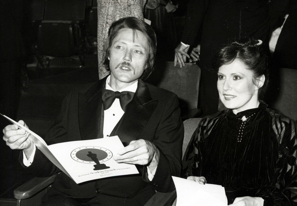 I don't know who these people are. They are seated, dressed in formal attire and holding documents at an event