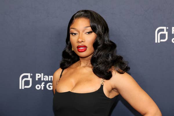 Megan Thee Stallion poses at the event, wearing a black dress with gold accents and characterized by her long, wavy hairstyle. Background has Planned Parenthood logos