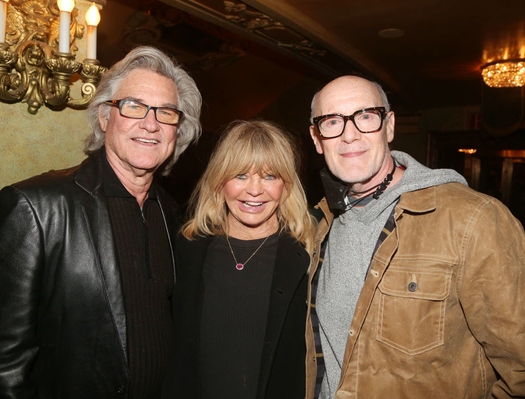 Kurt Russell, Goldie Hawn, and James Gunn smiling together at an event, with Kurt in a leather jacket, Goldie in casual wear, and James in a jacket and hoodie