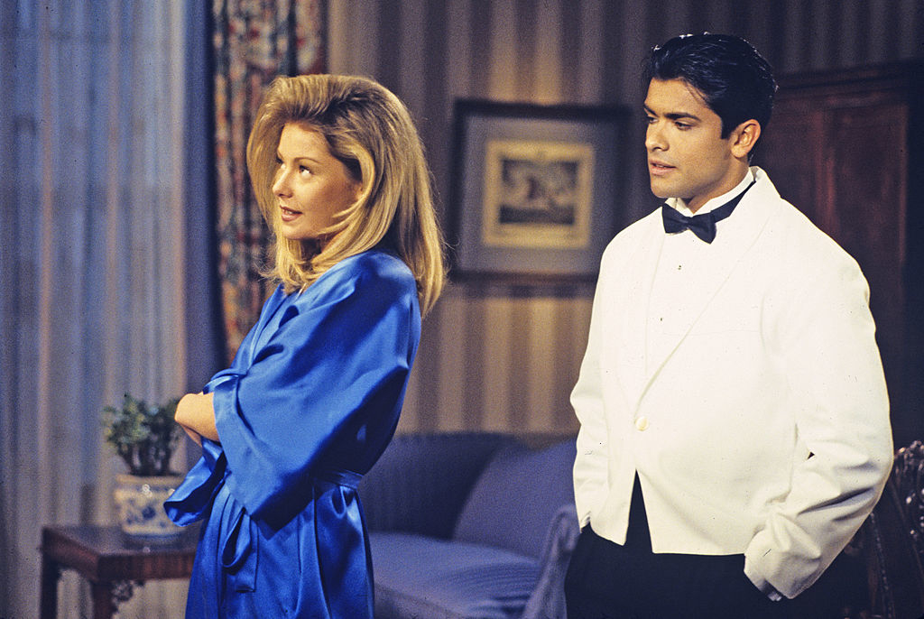 Cybill Shepherd in a luxurious robe speaks with Billy Dee Williams in a white tuxedo in an elegant, classic room