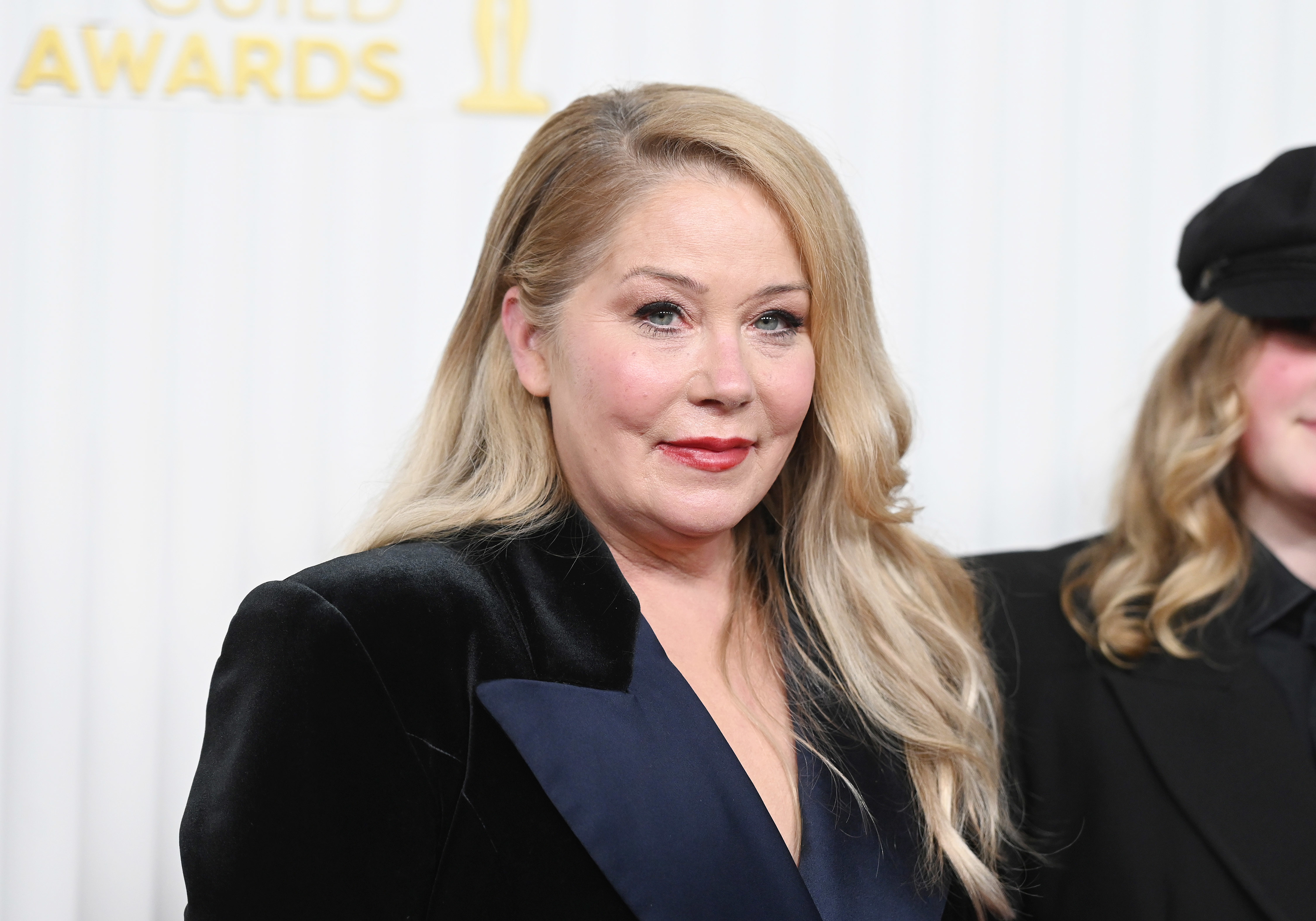 Christina Applegate poses at an event in an elegant, black outfit with a subtle smile