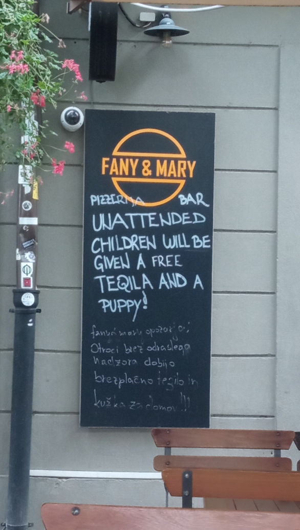 Chalkboard sign for Fany & Mary restaurant reads: "Unattended children will be given a free tequila and a puppy.” Text is in English and Polish