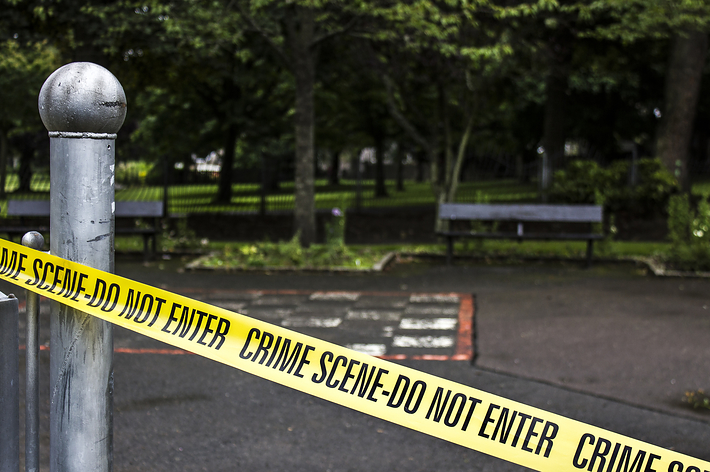 公園内でベンチ周辺を囲む「CRIME SCENE-DO NOT ENTER」テープ。