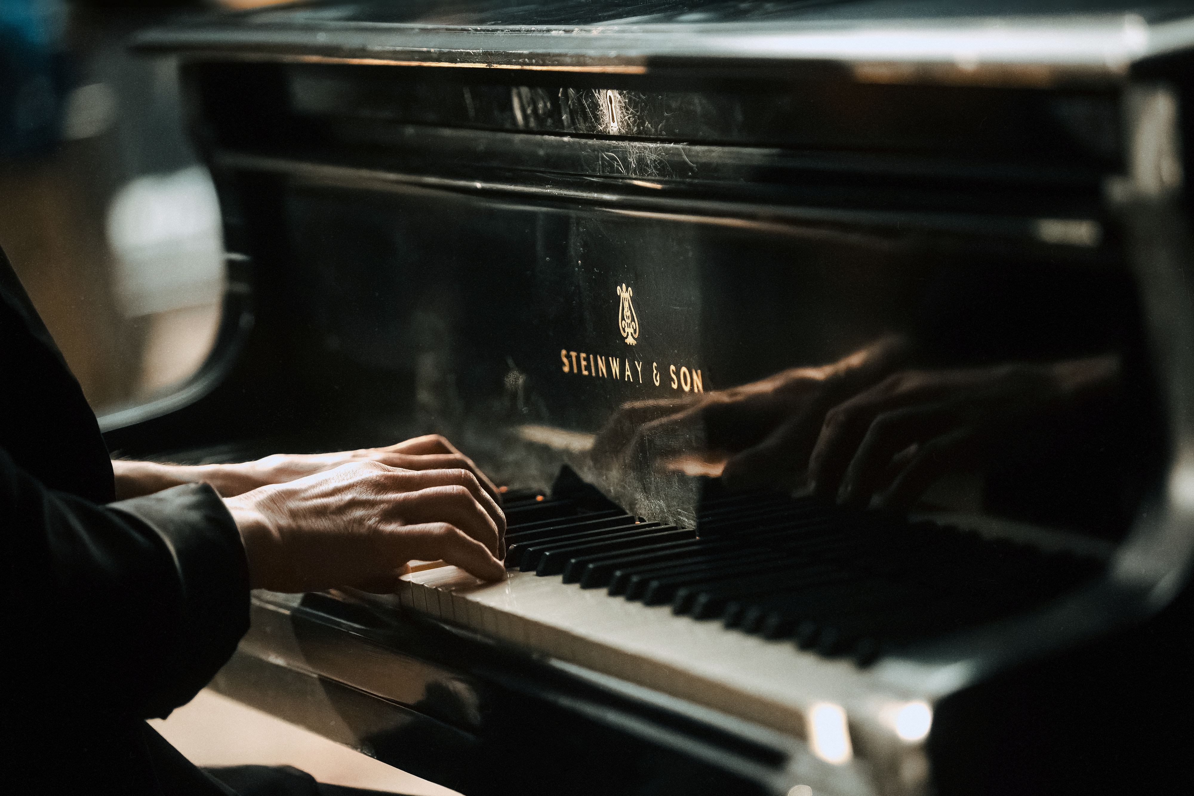 A person is playing a Steinway & Sons piano, with focus on their hands and the piano keys