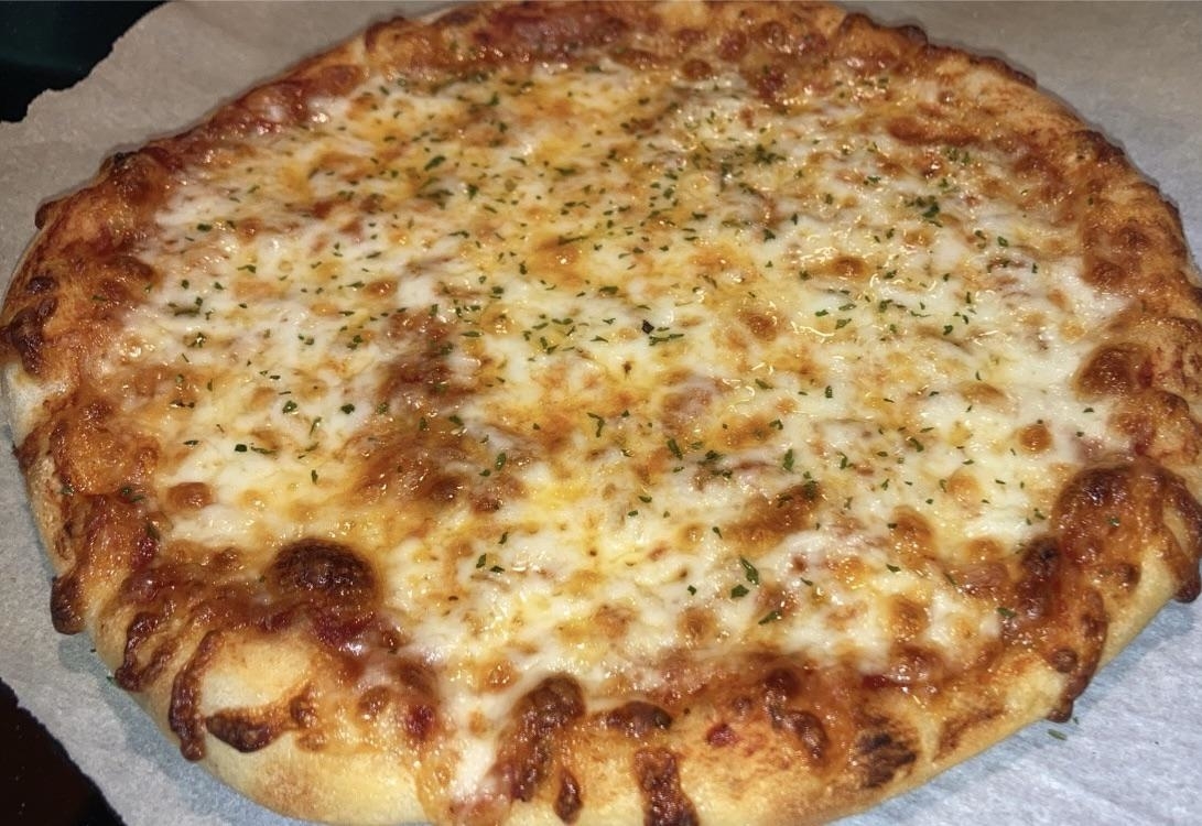 A close-up of a baked cheese pizza with visible melted cheese and sprinkled herbs on top