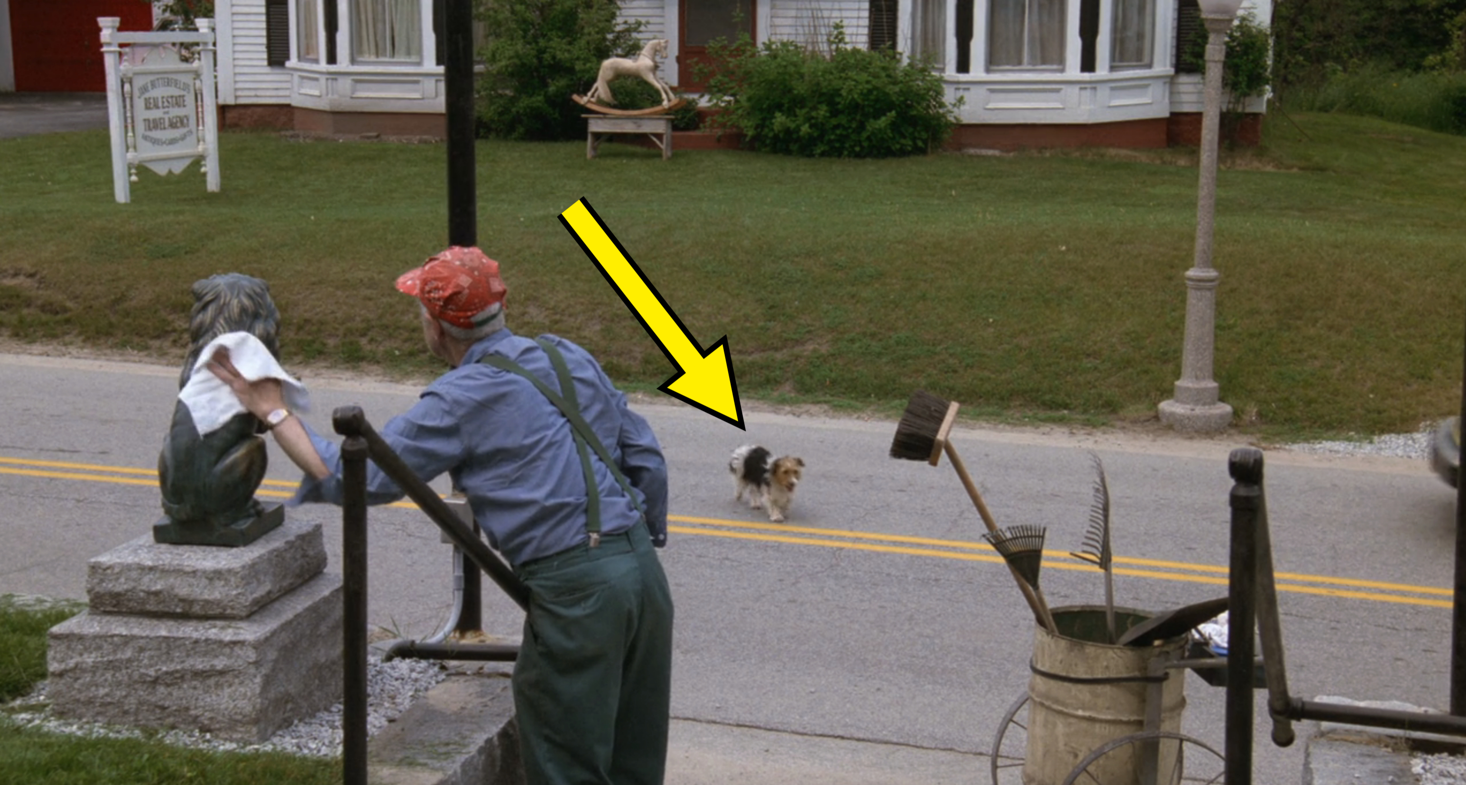 An elderly man in overalls and a red cap looks at a small dog running down a suburban street. A metal sculpture and gardening tools are nearby in "Beetlejuice"
