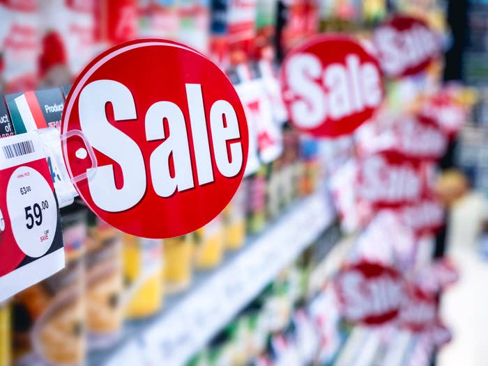 Red sale signs hanging in a grocery store aisle, indicating discounted prices on various products