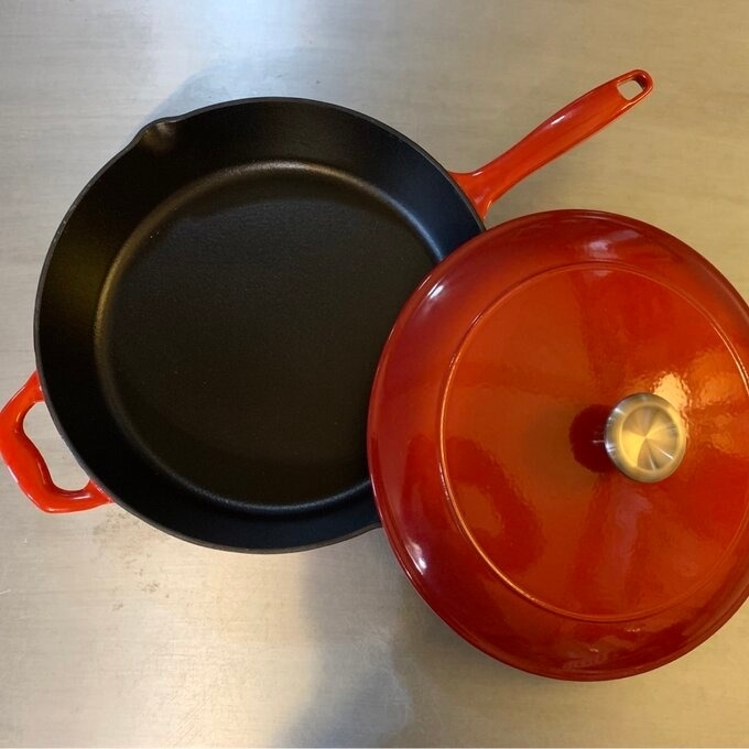 A cast iron skillet and a red enameled cast iron pot with lid on a kitchen countertop