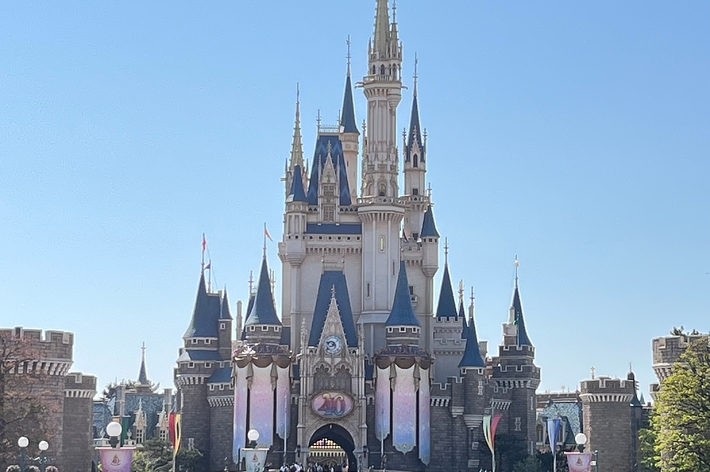 ディズニーランドのシンデレラ城と、その前にいる多くの訪問者たち。