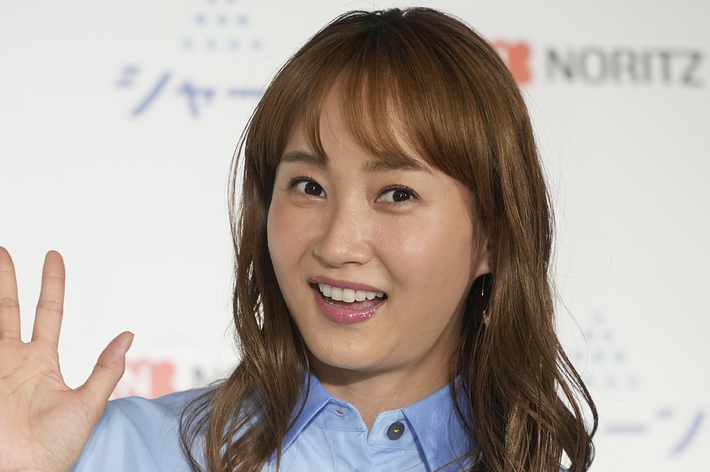 藤本美貴さんが白い背景の前で手を振っている。