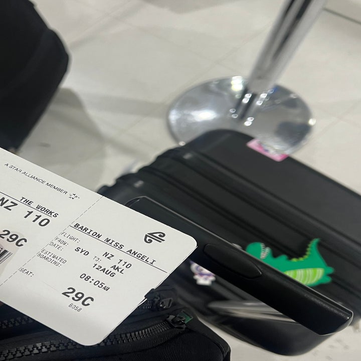 solo trip to japan itinerary A hand holds an Air New Zealand boarding pass for Andrew Will Angell, while standing near black luggage at an airport terminal