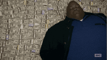 Huell Babineaux is lying down on a pile of cash