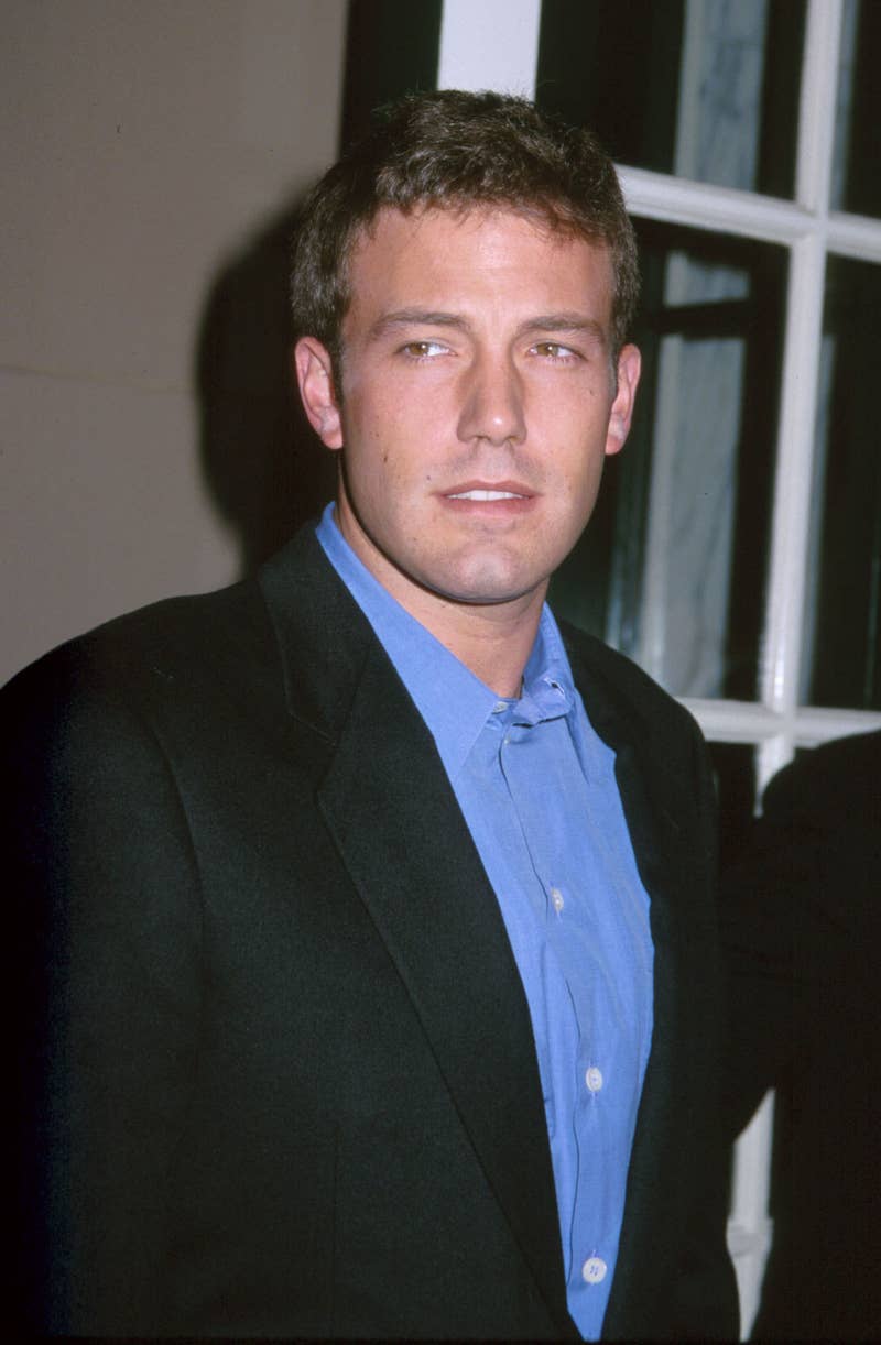 Ben Affleck stands in a suit jacket and blue shirt