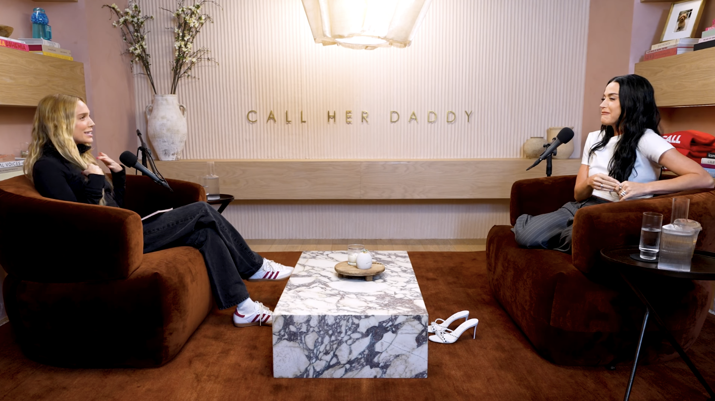 Alex Cooper and Cara Delevingne having a conversation in a living room setting for the "Call Her Daddy" podcast
