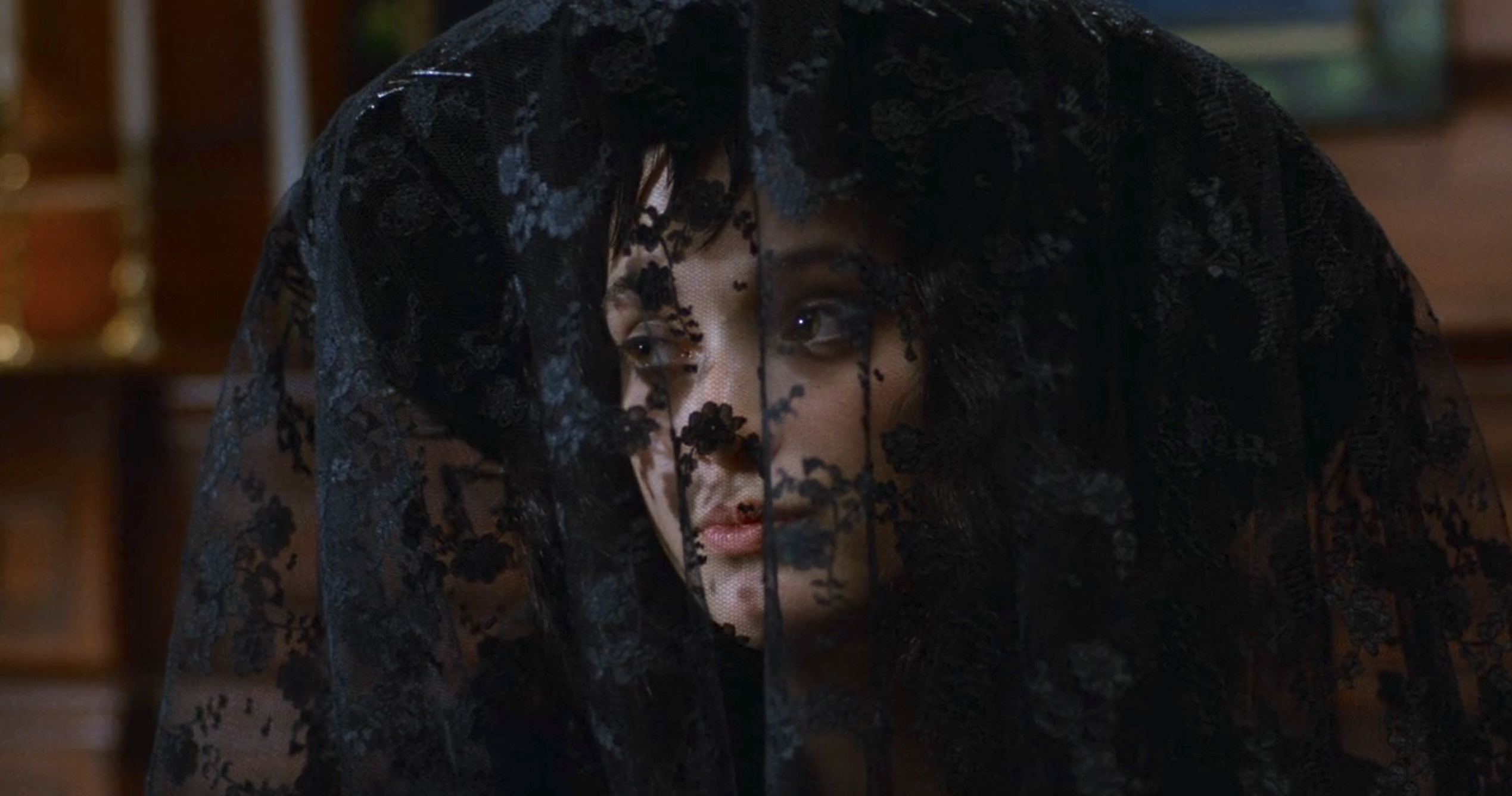 Winona Ryder is dressed in a black lace veil, partially obscuring her face, in a scene from "Beetlejuice."