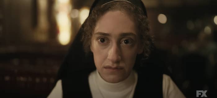 A woman dressed as a nun, looks intensely at the camera in a dimly lit setting from an FX series