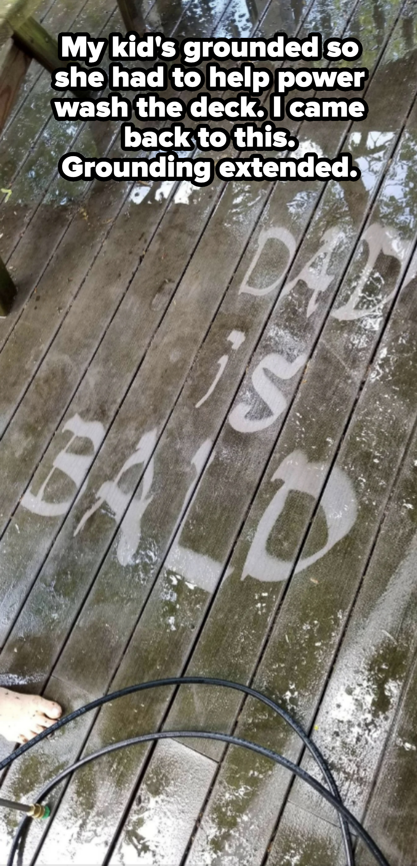 Wooden deck floor with the text "MY DAD IS BALD" visible due to pressure washing