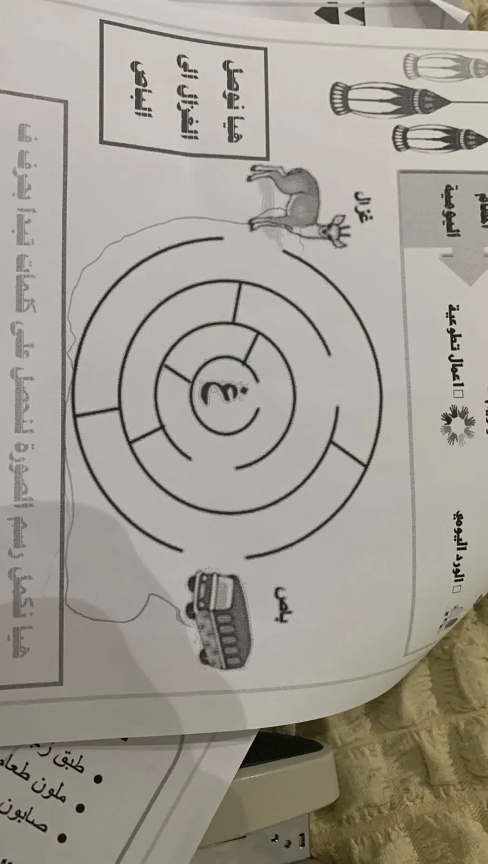 Arabic worksheet with a target, bus, and deer illustration. Sections read "color the picture," "draw the route," and contain drawing instructions, but the kid has drawn a route around the maze
