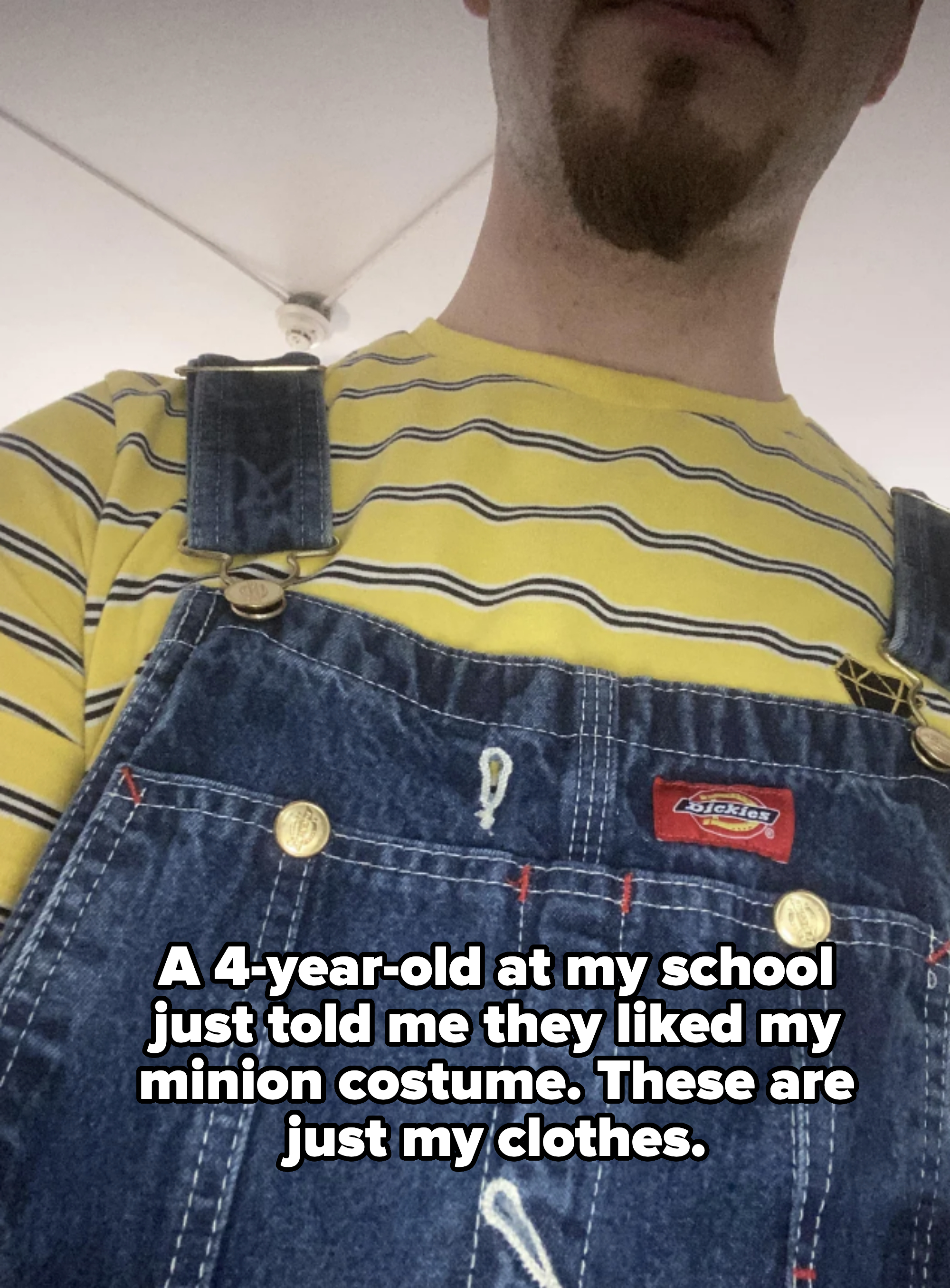 A person wearing denim overalls over a yellow and black striped shirt captioned "a 4-year-old at my school just told me they liked my minion costume - these are just my clothes"