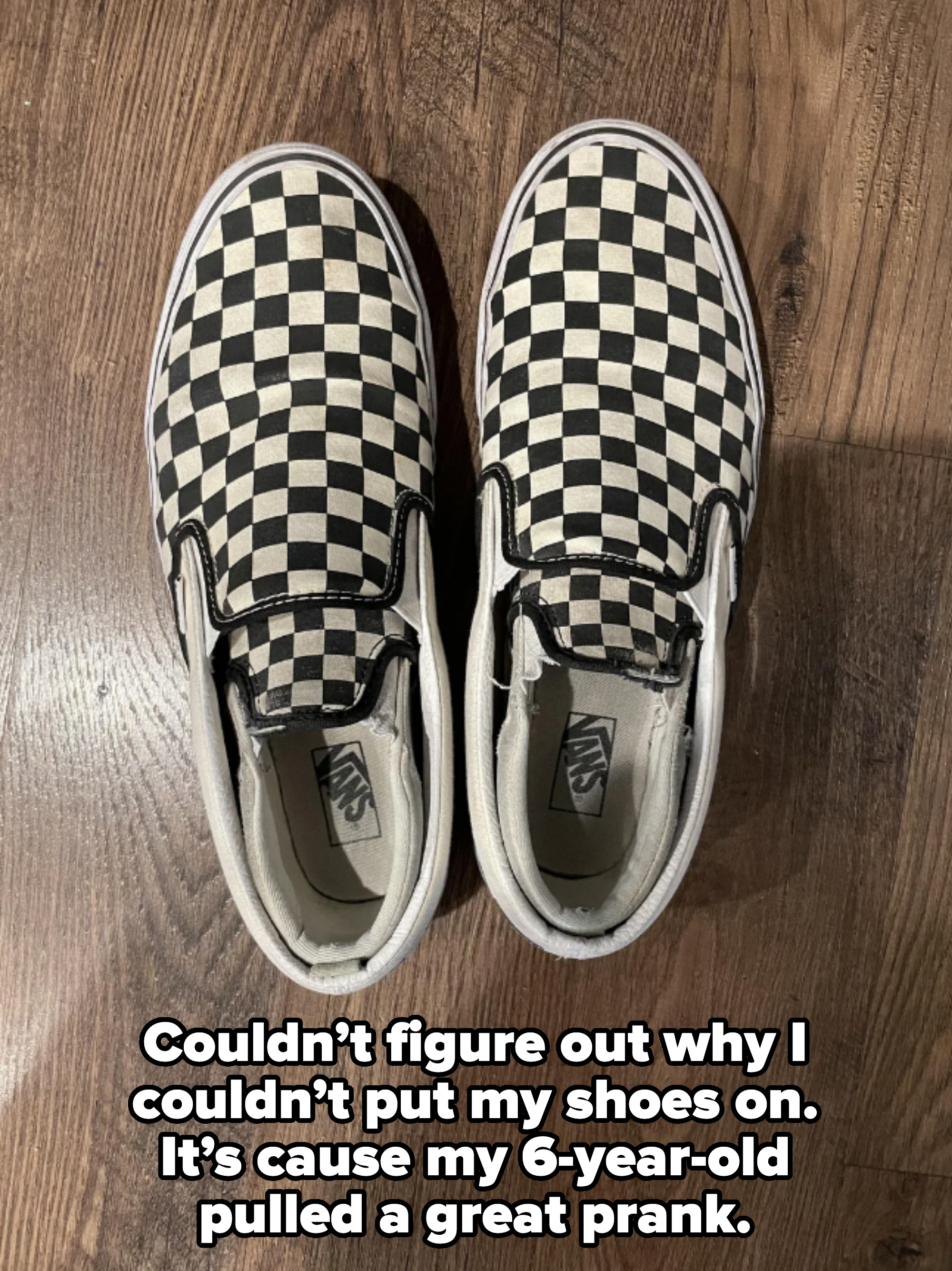 Black and white checkered Vans slip-on shoes on a wooden floor, with smaller shoes inside