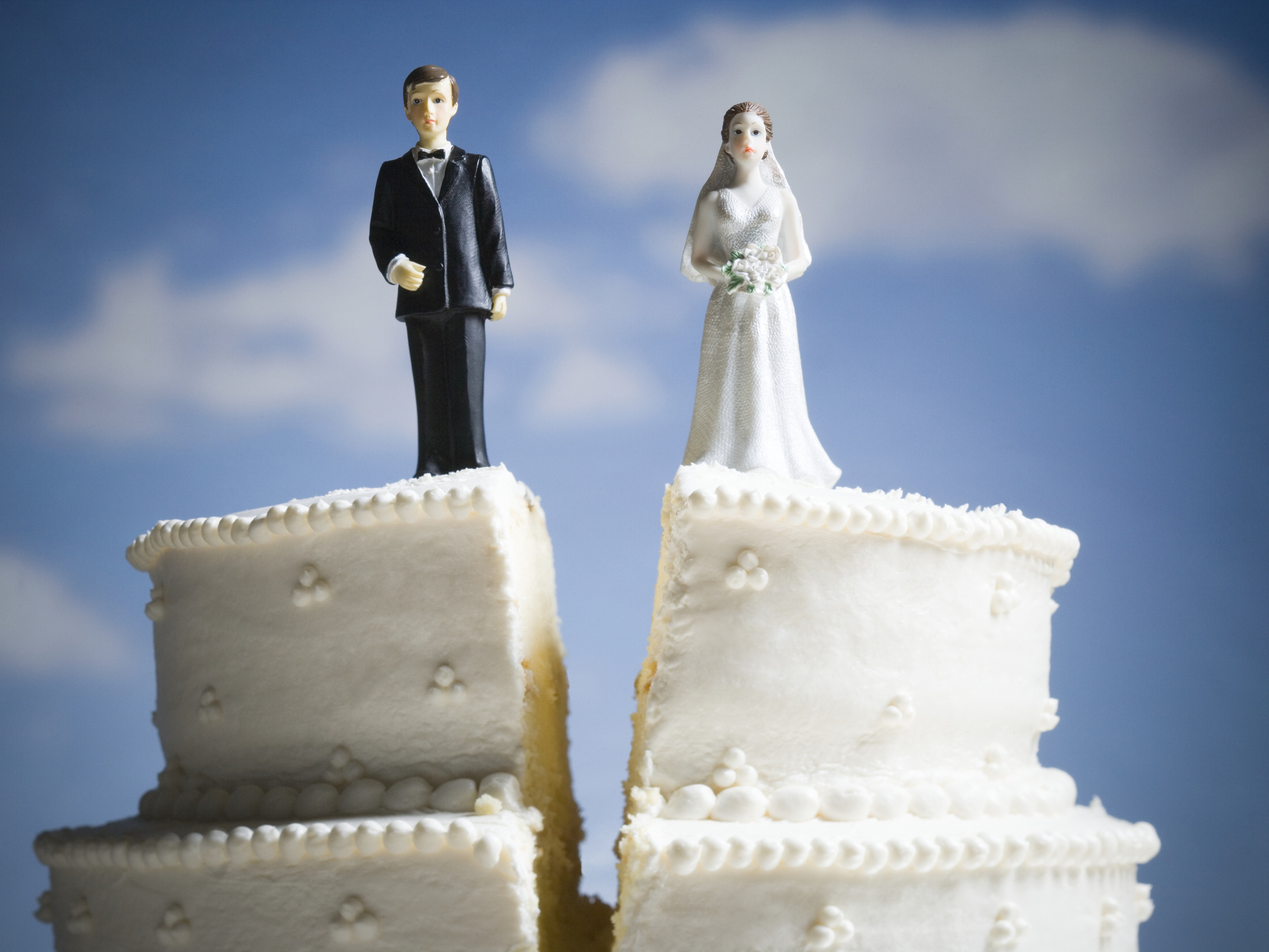 Bride and groom cake toppers on two separate cake slices with a split, symbolizing separation or divorce