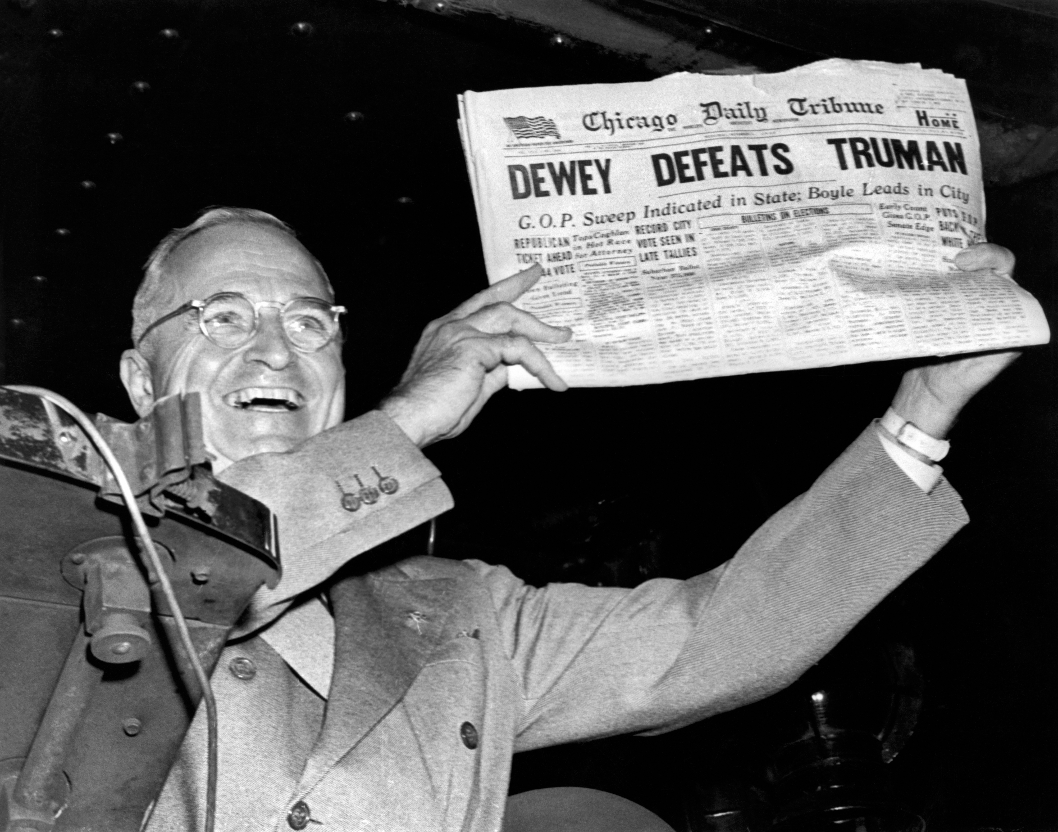 Harry S. Truman holding a "Chicago Daily Tribune" newspaper with the headline "Dewey Defeats Truman," smiling confidently