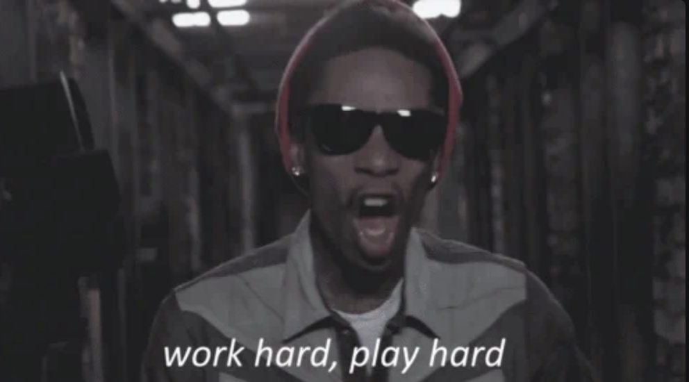 A person in sunglasses and a red hat is singing with the text "work hard, play hard" visible below