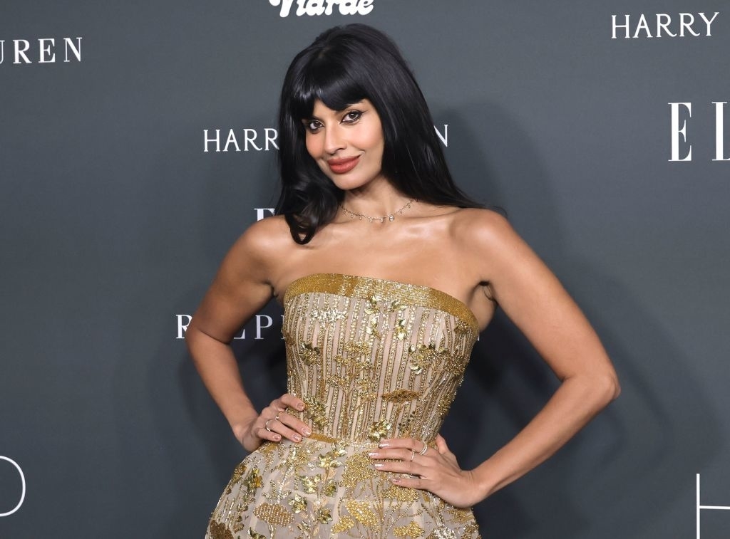 Jameela Jamil poses on the red carpet in an elegant strapless dress with intricate detailing at an event