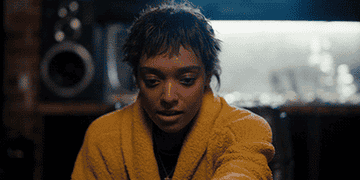 Sophie Wilde looks down with concern while wearing a cozy bathrobe in an indoor setting