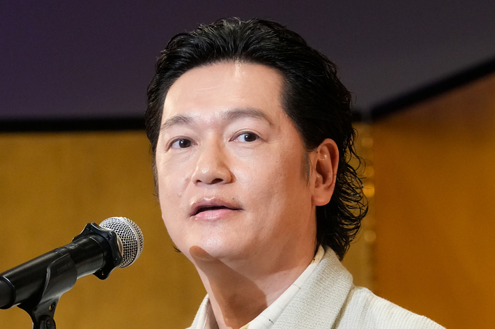 井浦新さんがスーツ姿でスピーチしている。