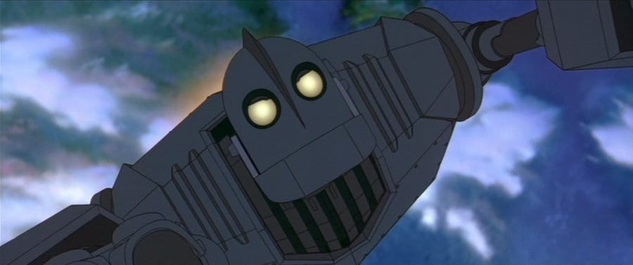 The Iron Giant flies at an angle with glowing eyes against a cloudy night sky