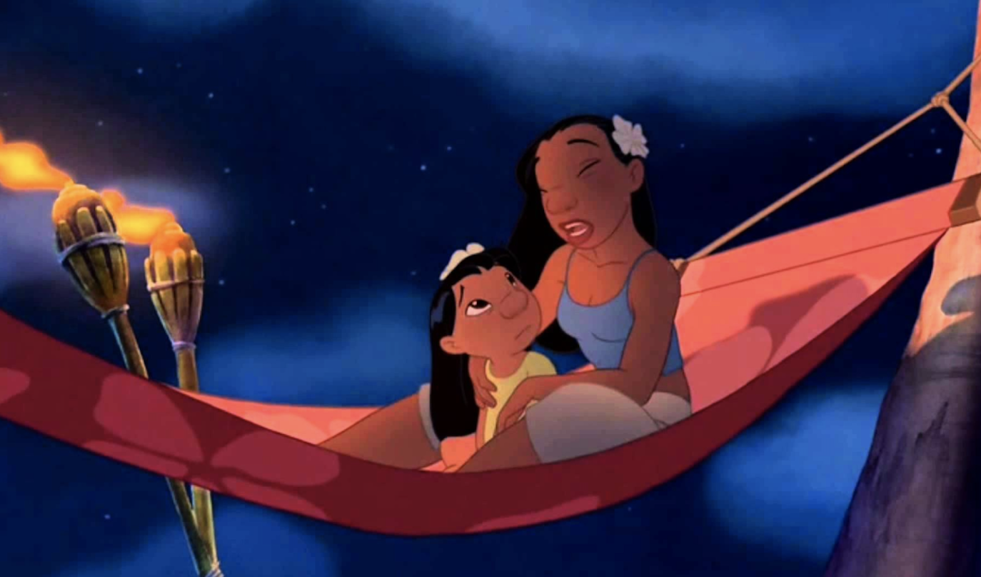 Lilo and Nani from "Lilo & Stitch" share a tender moment on a hammock, with tiki torches in the background