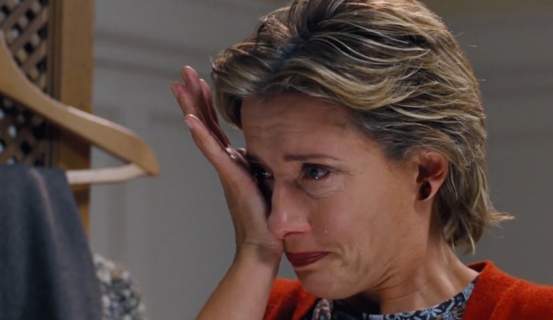 Emma Thompson, teary-eyed, wipes a tear from her face using her hand, in a scene from a film. She appears emotional and distressed