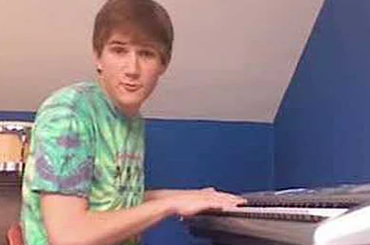 Bo Burnham playing the keyboard, wearing a casual tie-dye shirt, in a home setting
