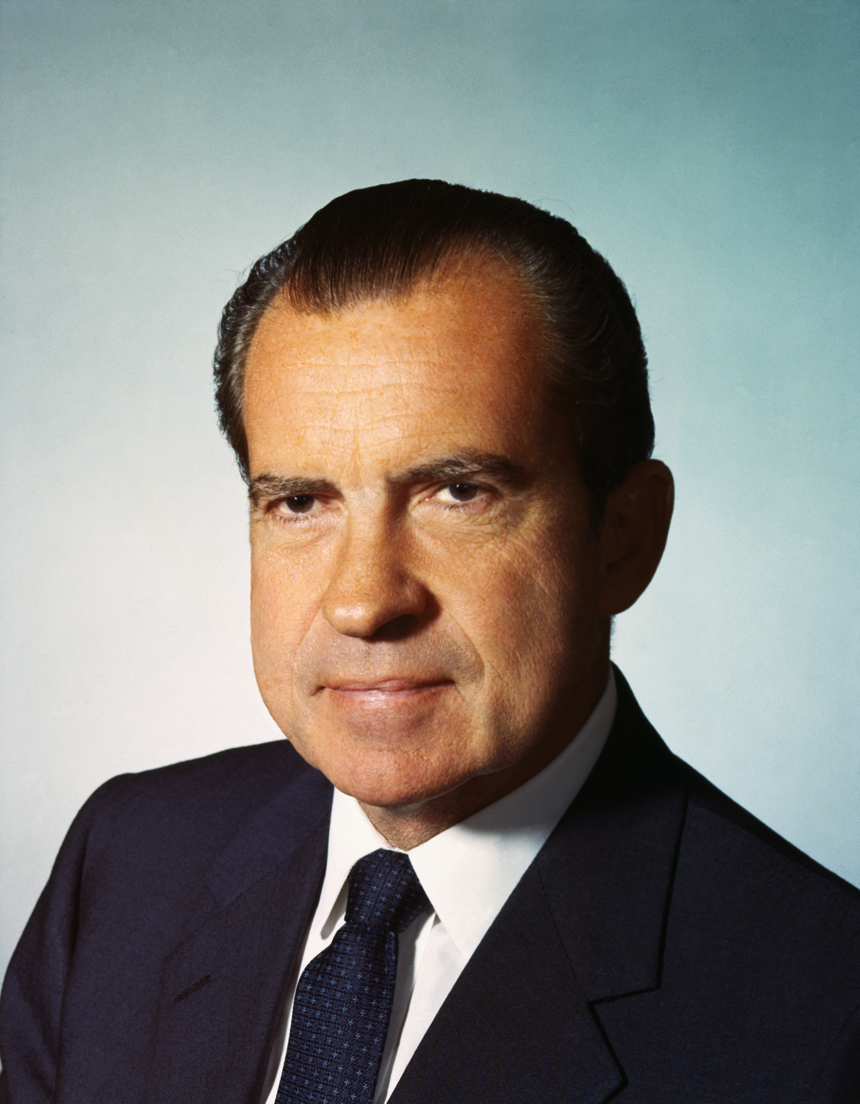 Richard Nixon in a formal portrait, wearing a dark suit and tie, with a neutral expression, against a plain background
