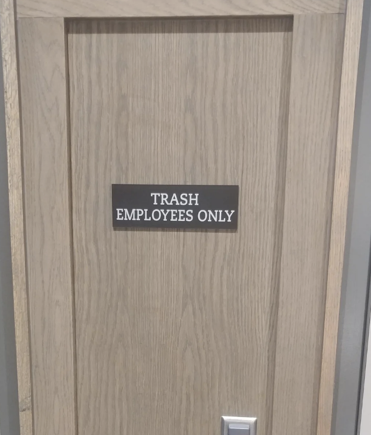 The image shows a wooden door with a sign that reads "TRASH EMPLOYEES ONLY"
