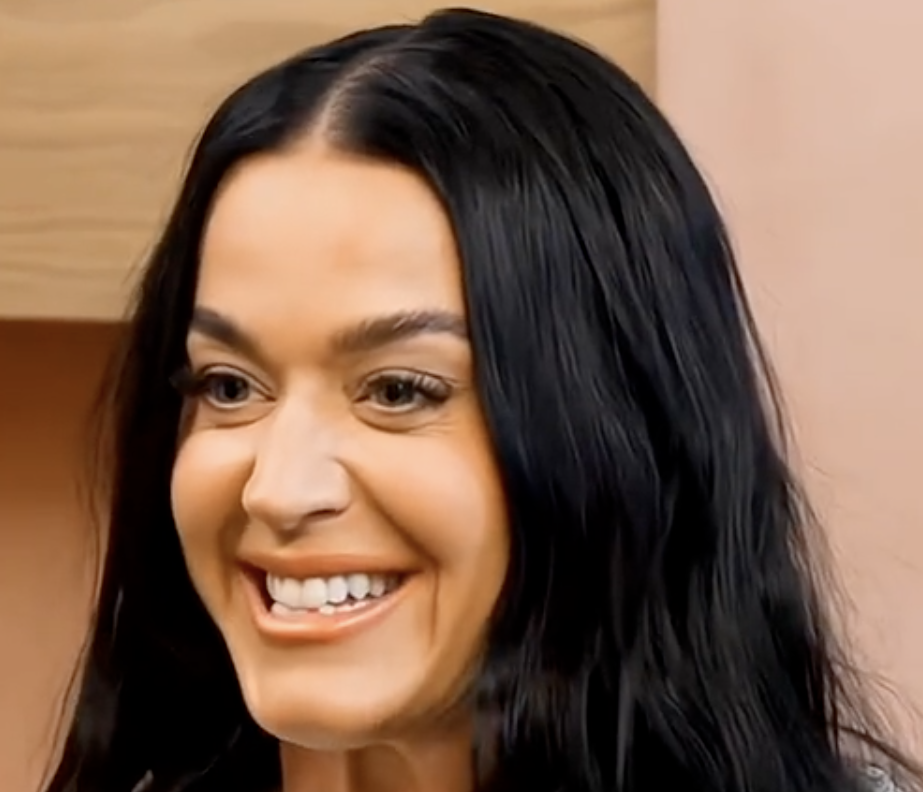 Katy Perry smiling and speaking into a microphone