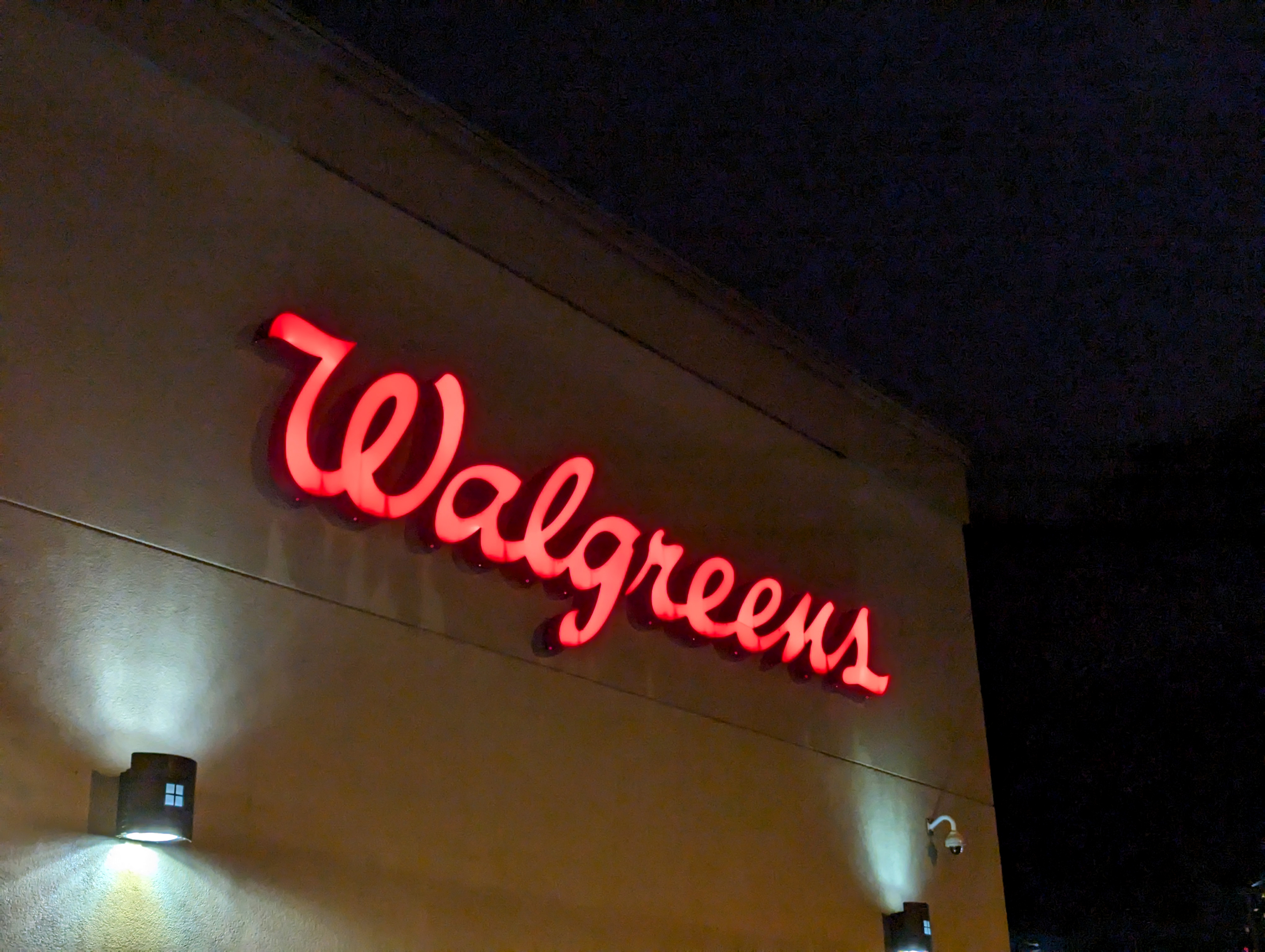 A Walgreens store's neon sign glows brightly against the night sky