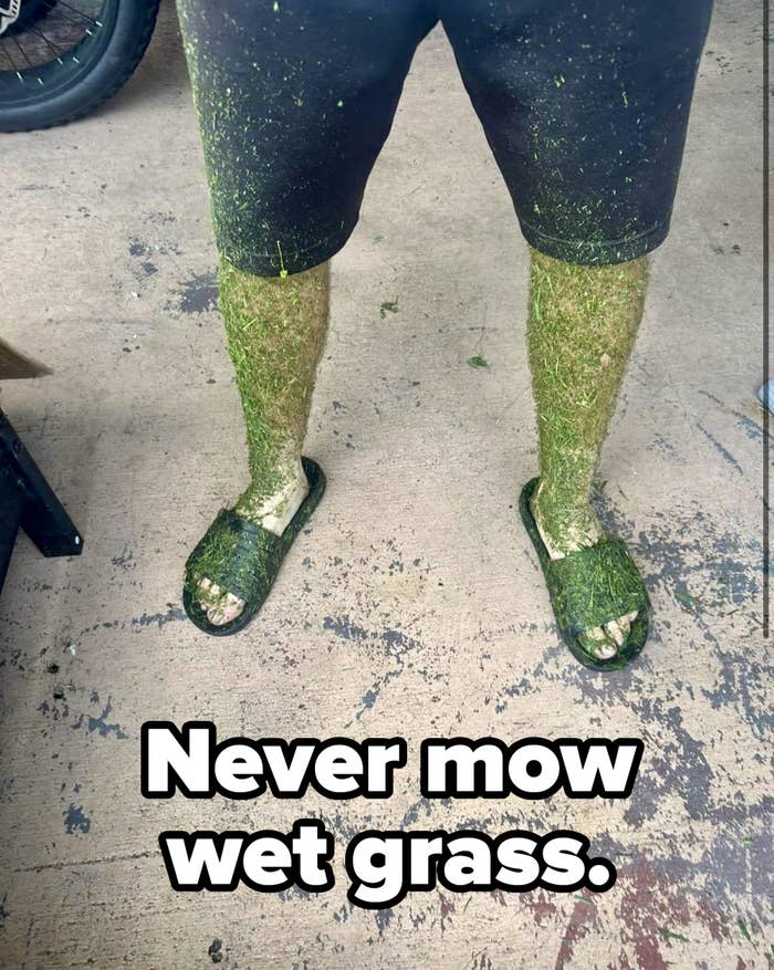 Person wearing black shorts and sandals standing on a concrete floor with legs and sandals covered in grass clippings. Faces of individuals not shown