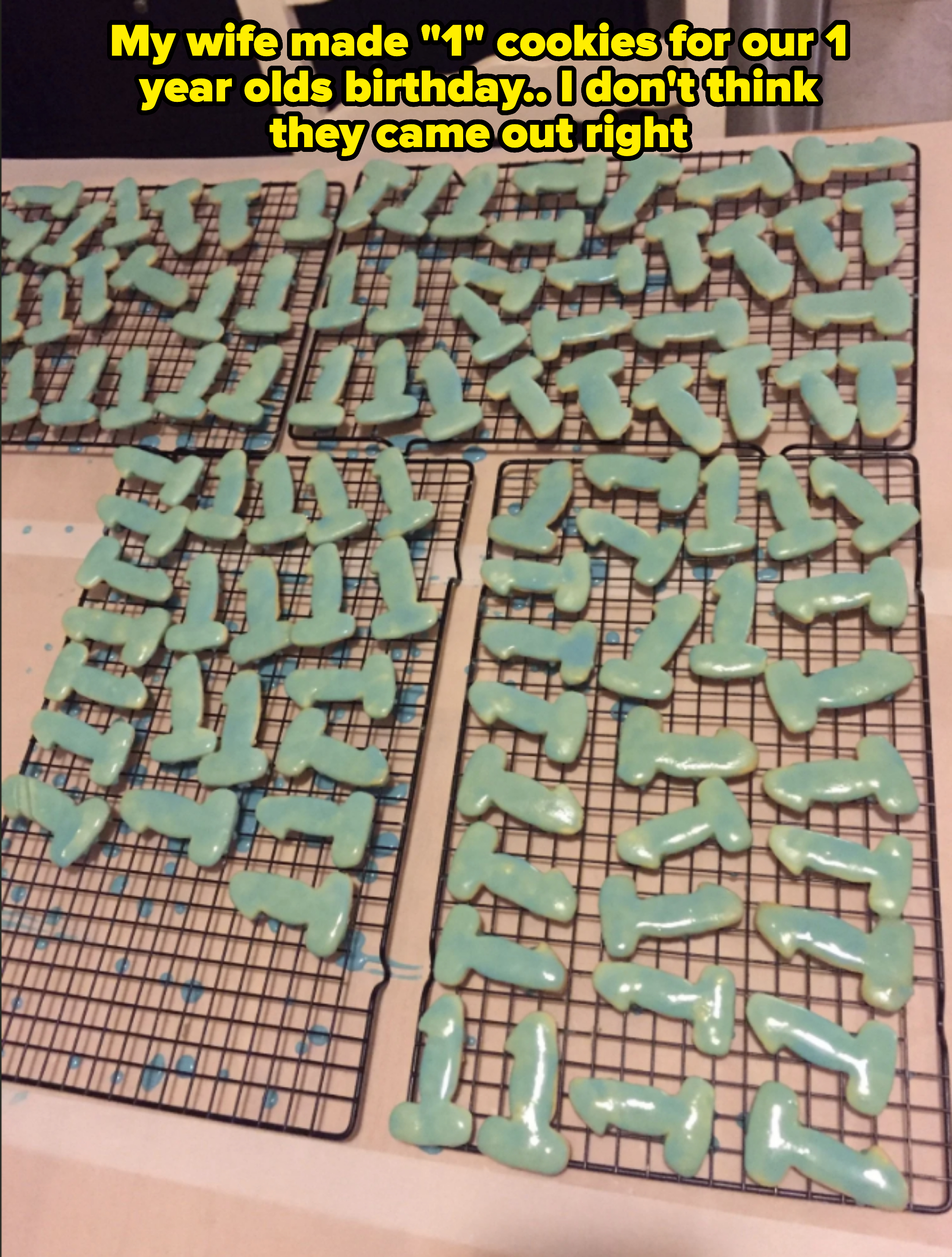 Dozens of hammer-shaped cookies with blue icing are cooling on wire racks placed on a table