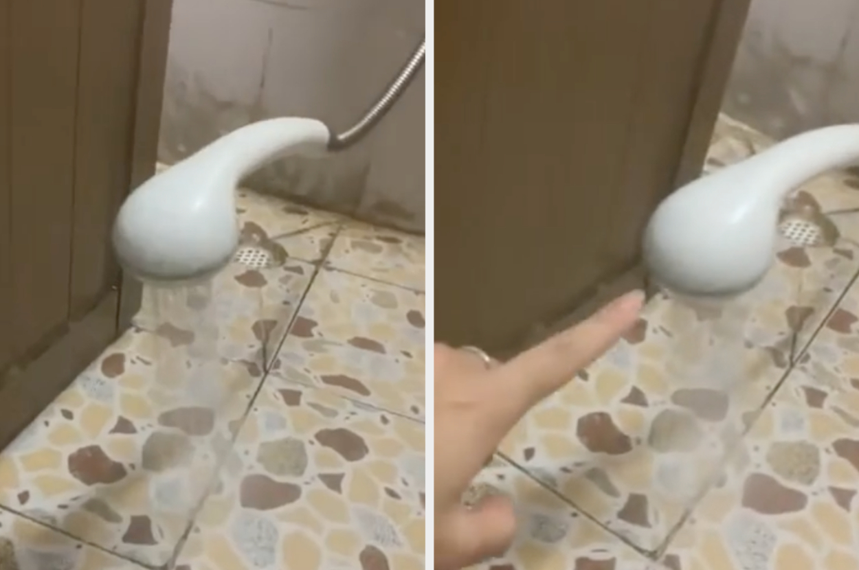 A person touches a showerhead that appears to make water flow upwards, likely due to a special effect. Bathroom floor tiles are visible