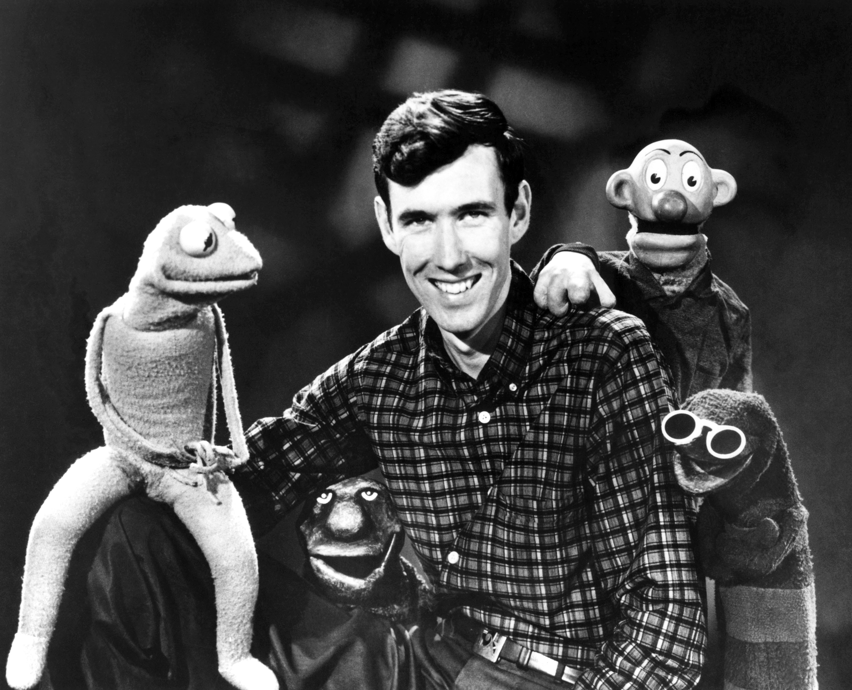 A smiling man poses with four classic puppet characters: Kermit the Frog, Rowlf the Dog, Snerf, and Harry the Hipster