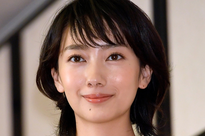 広瀬すずさんが薄い色のトップを着て、賞を受賞しトロフィーを持っています。