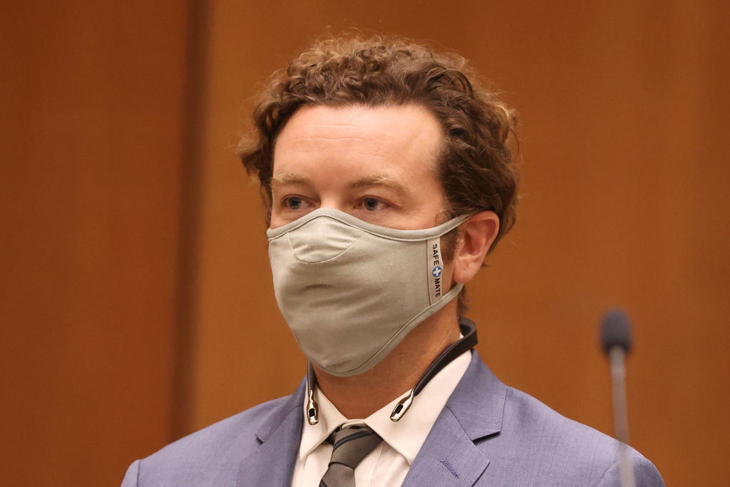 Danny Masterson wearing a suit and a face mask, standing in a formal setting
