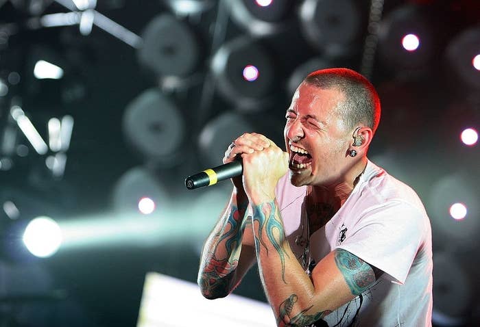Man with tattoos passionately singing into a microphone on stage