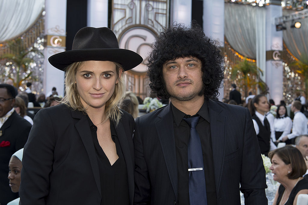 Aimee Osbourne and Cedric Bixler-Zavala at a formal event, both dressed in black jackets; Aimee wears a hat